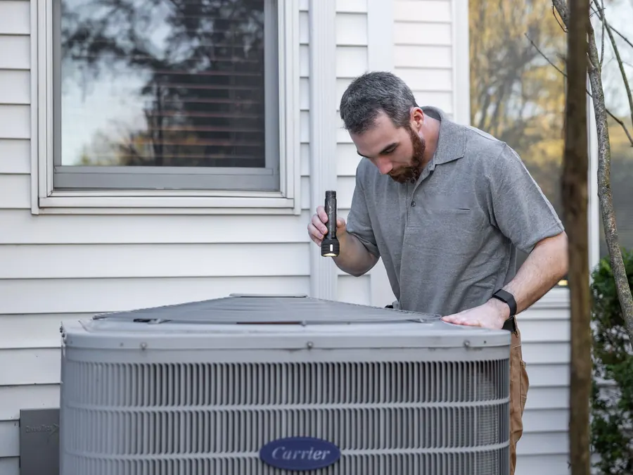 HVAC technician inspecting outdoor air conditioning equipment